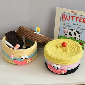 Detail of cute woven cotton rope storage basket with lid showing texture and cartoon eyes