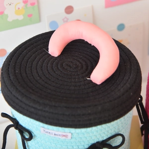Detail of hand-woven light blue storage basket with black bow and pink handle