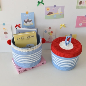 Detail of woven cotton storage baskets with blue stripes and decorative red pom-poms