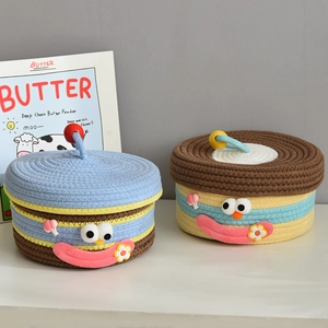 Detail of two cartoon woven storage baskets with cute facial expressions and lids