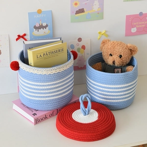 Detail of blue and white striped woven storage baskets with lace trim and red pompoms