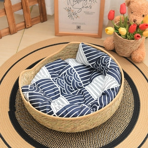 Detail of round woven seagrass pet bed with a blue wave pattern cushion inside