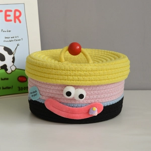 Detailed view of handmade woven cotton rope storage basket with cartoon face and lid