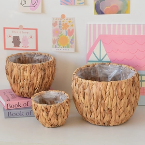 Three sizes of woven grass planters with waterproof plastic liners on a white tabletop