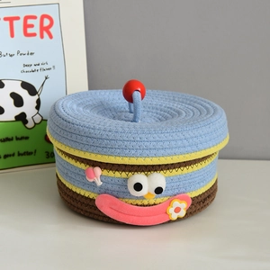 Detailed view of woven storage basket featuring a colorful cartoon face and red ball handle