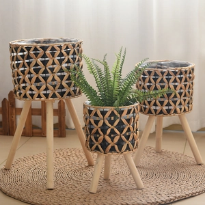 Close-up of handwoven wicker planters with wood tripod stands and waterproof inner liners