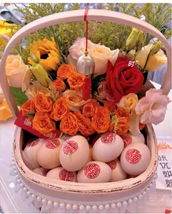 Close-up of a woven flower basket with red roses, eggs, and a Chinese Xi wedding symbol