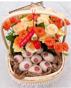 Detailed close-up of a woven flower basket with orange roses and eggs featuring Xi symbols