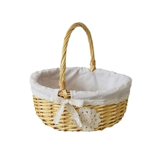 Handwoven wicker flower basket with lace lining and bow decoration on white background
