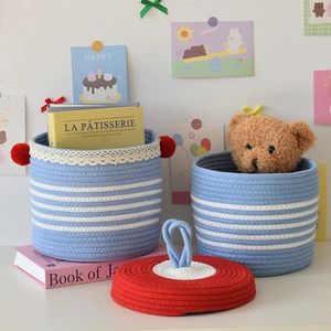 Close-up of sky blue woven cotton rope storage baskets with white lace and pom poms