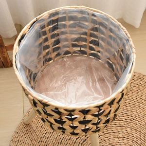 Detail view of woven plant basket with waterproof liner and three solid wood support legs