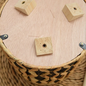 Close-up of the solid wood base and tripod legs on a handmade woven seagrass plant stand
