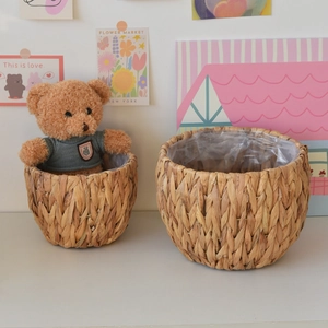Detail of woven straw plant baskets with waterproof lining and decorative teddy bear