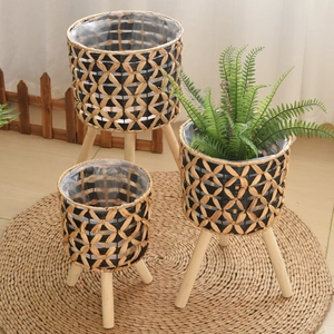 Detailed set of three handwoven planters with natural grass texture and sturdy wooden legs