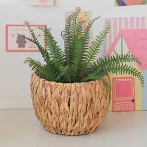 Close-up of a lush faux Boston fern in a hand-woven natural seagrass basket planter