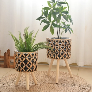 Detail of hand-woven plant stands with natural fiber patterns and solid wood tripod legs