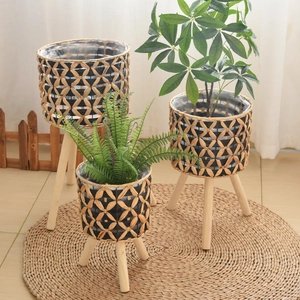 Detail of three hand-woven planters with wooden legs and protective plastic lining
