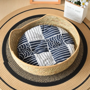 Top view of hand-woven straw cat bed with a blue geometric cushion and floral decor