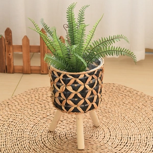 Detail of hand-woven fiber planter with wooden tripod legs and clear waterproof liner