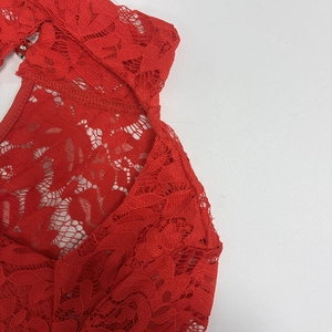Detail of red floral lace fabric featuring a back cutout with a sparkling rhinestone button