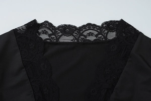 Macro view of the intricate black floral lace neckline detail on a stylish woman's top