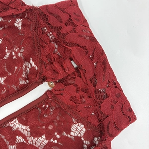 Detailed close-up of wine red lace fabric with intricate floral patterns and stitching