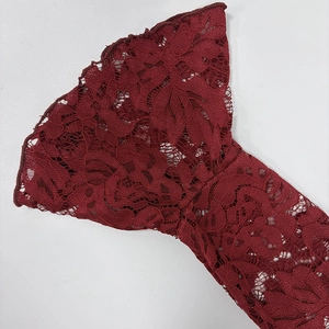 Close-up of elegant flared lace sleeves in wine red with detailed floral cutouts