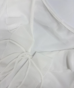 Detail view of tiered ruffles and delicate drawstring on a white lace beach dress