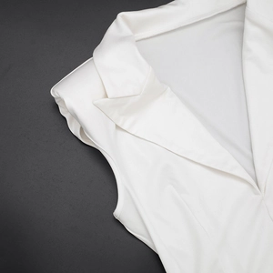 Détail du revers élégant et des épaulettes structurées sur la robe blanche sans manches