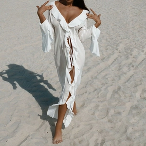 Detail of white long-sleeved beach cover-up with ruffled edges and sheer fabric