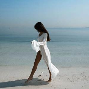 Detailed view of white beach cover-up featuring ruffled V-neck and high side slits