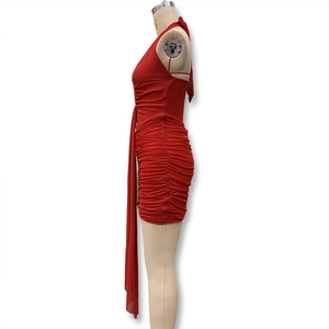 Detail of red bodycon mini dress featuring lateral ruching and side hanging ribbon