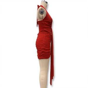 Detail of red halter neck ruched bodycon dress with hanging decorative sash feature