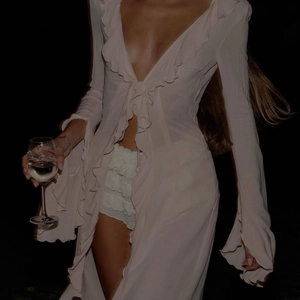 Detail of light pink chiffon cardigan featuring tiered ruffles and delicate lace-up closure
