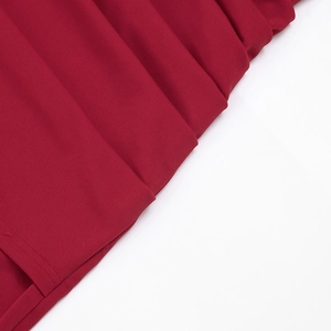Détail de l'ourlet de la robe rouge foncé montrant des plis verticaux et des coutures fines