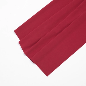 Vue détaillée de la texture du tissu tissé rouge foncé et drapé élégant sur la robe