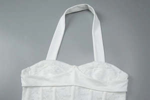 Dettaglio del top bianco in pizzo con scollo a cuore e struttura a stecche stile bustier