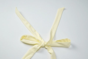 Close-up of cream yellow halter top back straps with textured knit bow detail