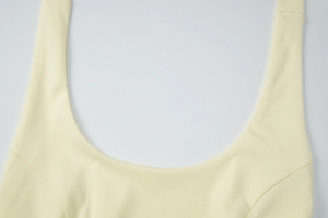Close-up of pale yellow ribbed knit top featuring wide straps and refined U-neckline stitching