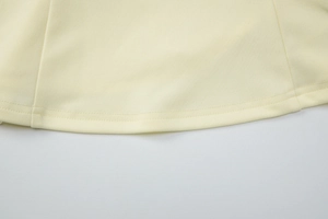 Detailed macro view of the double-stitched hem on the yellow slim halter top