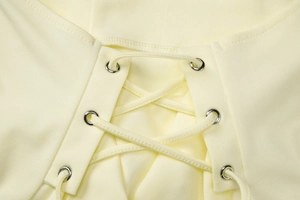 Close-up of lace-up detail on yellow crop top with metal eyelets and cross ties