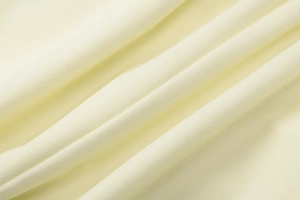 Macro shot of cream-colored knitted fabric texture with soft drapes and fine weave details