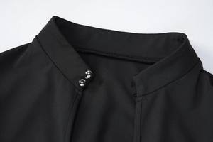Détail de la robe moulante noire avec col montant et boutons de perles argentées