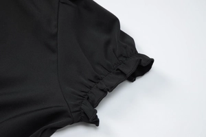 Détail de la manche d'une robe noire avec volants élastiques et coutures impeccables