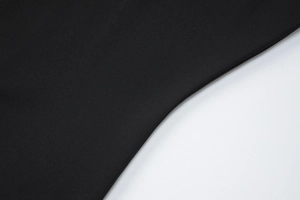 Gros plan sur la texture du tissu en maille noire de la robe courte tendance