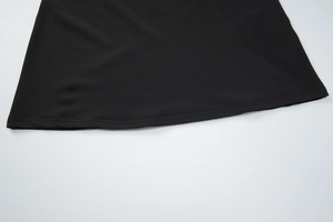 Gros plan de l'ourlet de la robe noire montrant les détails de couture à double aiguille
