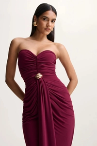 Detail of elegant wine red strapless gown featuring ruched fabric and gold metal waist buckle