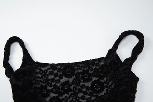 Détail de la robe en dentelle noire montrant les broderies florales et les bretelles