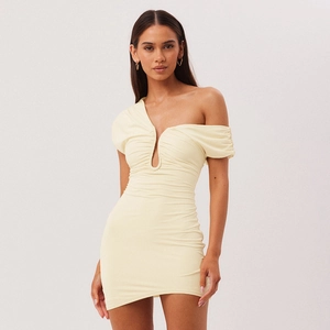 Détail de la robe moulante crème avec fronces et décolleté asymétrique élégant