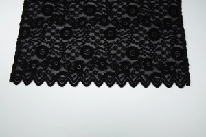 Gros plan sur un tissu en dentelle noire avec broderie florale et bords festonnés